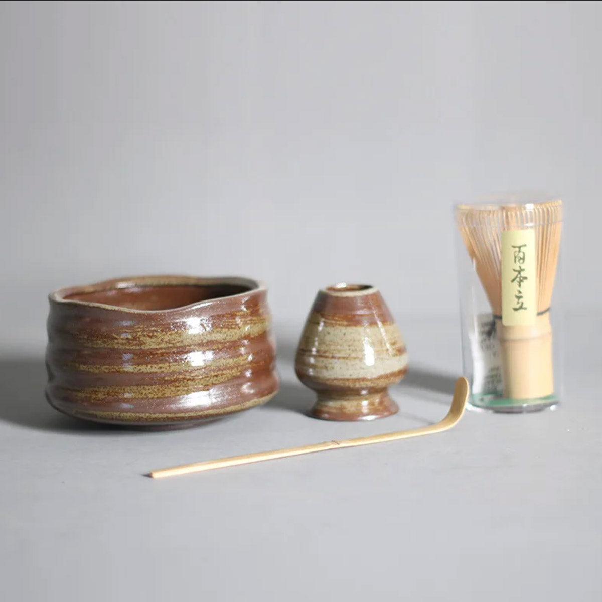 Set of ceramic containers with a whisk on a gray background