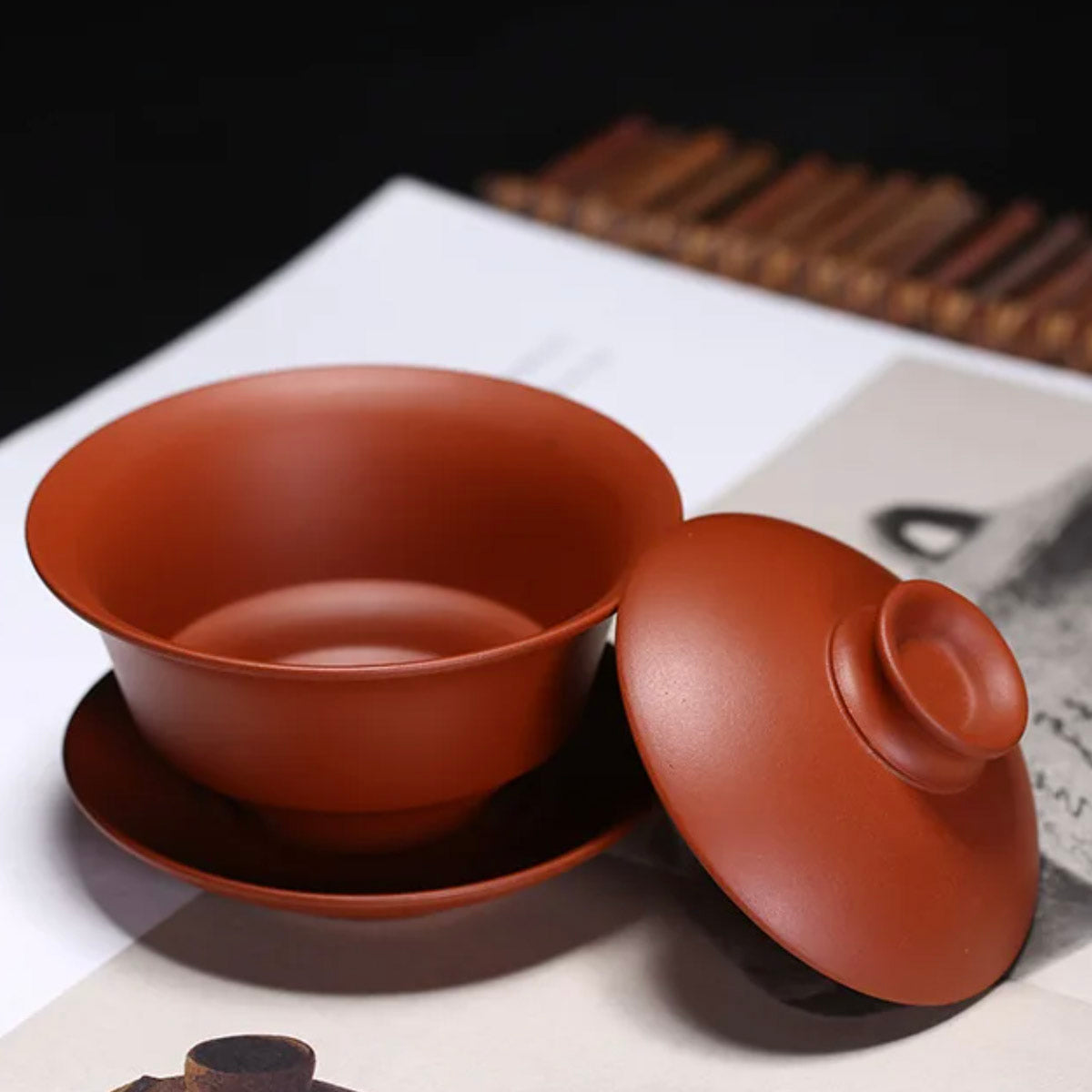 Red clay teacup with lid on a newspaper background