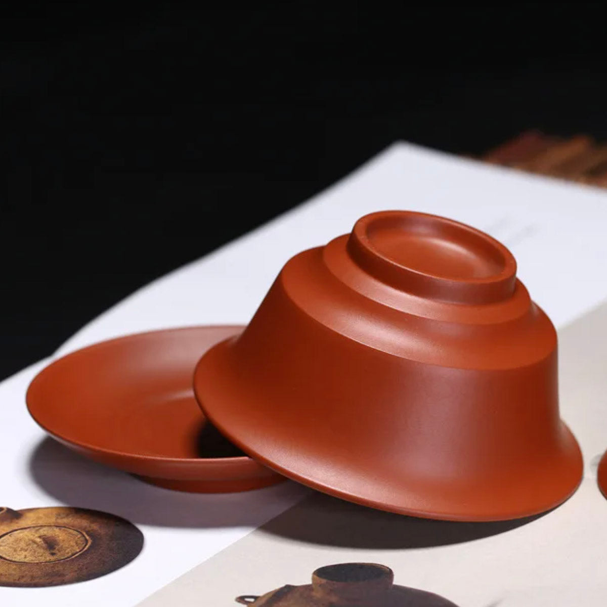 Red ceramic bowl on a white surface with a dark background